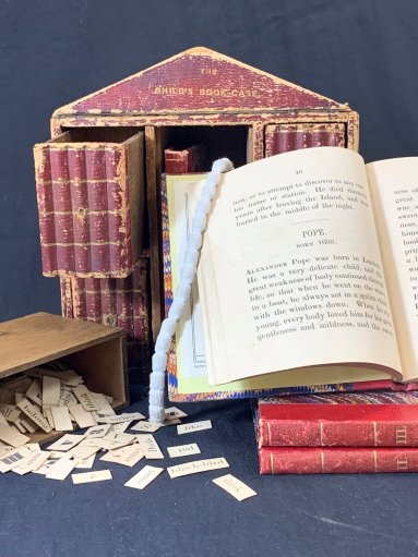This small bookcase contains four non-fiction, educational books in the centre: Child’s First Book (Vol I), Stories from Genesis (Vol II), Stories from Natural History (Vol III), Biography (Vol IV). The drawers contain individual word cards and letters for making sentences.